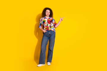 Full size photo of attractive young woman point empty space dressed stylish colorful print clothes isolated on yellow color background
