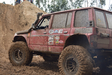 a red SUV in the mud accelerates to overcome obstacles. Off-road competition for SUVs.