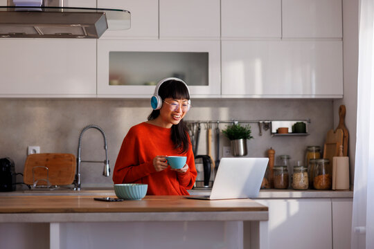 Woman drinking coffee and having online meeting while working from home