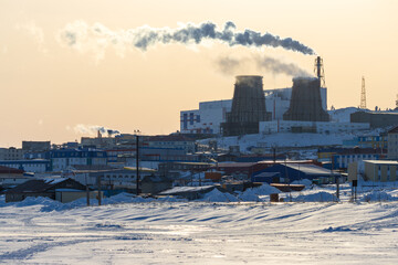 Winter arctic industrial landscape. View of the smoking chimneys and cooling towers of a thermal...