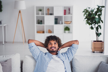 Photo of funky positive man wear checkered shirt arms behinh head staying home relaxing couch...