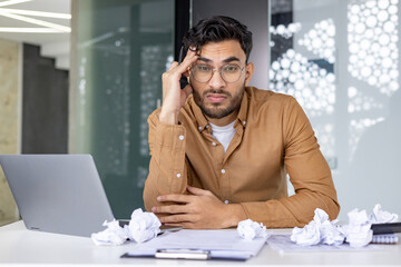 Frustrated young businessman dealing with stress and deadlines in modern office