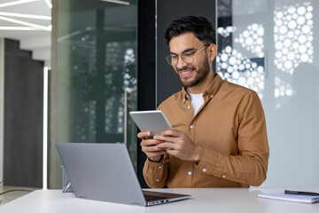 Young professional man using digital tablet at work in modern office setting