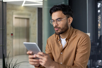 Focused man using a tablet in a modern office environment
