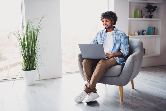 Photo of funky positive man wear checkered shirt working modern gadget staying home indoors house apartment room
