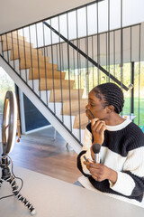 This image features a young Black woman engaging in her morning beauty routine, applying makeup...