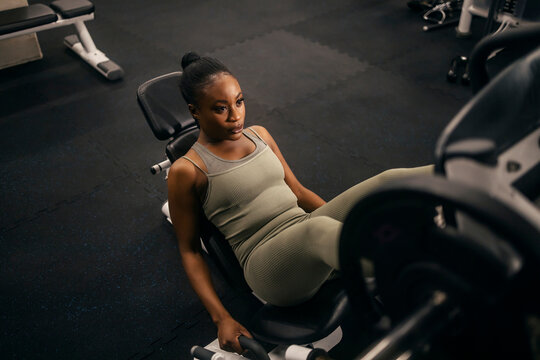 From above view of a strong black sportswoman doing workouts on a leg press machine.