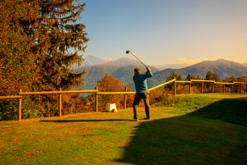 Golfer Teeing Off with His Driver on Golf Course Menaggio with Mountain View in Autumn in Lombardy,...