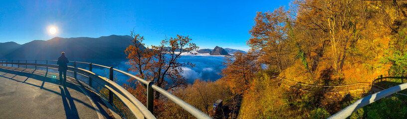 Fototapeta premium Panoramic View over Mountain Peak San Salvatore Above Cloudscape with Sunlight and Clear Sky in Lugano, Ticino in Switzerland.