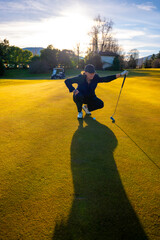 Female Golfer with Shadow on the Putting Green in Sunset with Lens Flare on Golf Course in...