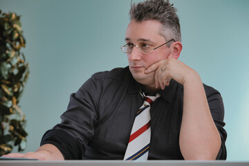 Man in glasses, thoughtful, resting chin, contemplating