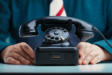 Contact us: Hands beside rotary phone, ready for communication