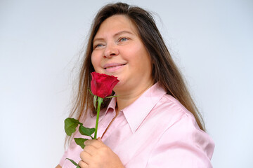 happy romantic mature woman with long hair holding bouquet of red roses in her hands, looking...