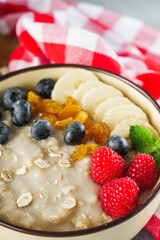 tasty nutritious oatmeal with fruits and berries on a light stone background