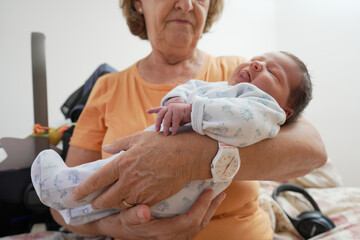 Elderly woman gently cradling a sleeping newborn in her arms, showcasing the peacefulness and...