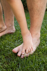 dad and son on a walk in the summer. Child and father together. Feet barefoot on green grass. Healthy lifestyle. Unity, games together. Father's Day
