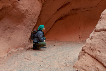 portrait of Latin male tourist squatting admiring the landscape inside rocky mountains in Jujuy,...