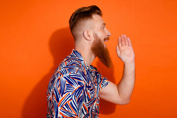Photo of shocked funky guy dressed print shirt shouting announcement empty space isolated orange...