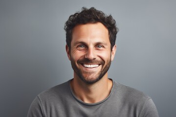 Obraz premium Portrait of a cheerful man in his 30s smiling at the camera in front of soft gray background