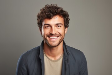 Portrait of a cheerful man in his 30s smiling at the camera isolated on soft gray background