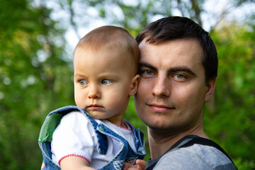 Portrait of little adorable serious girl and smiling father in spring outdoors
