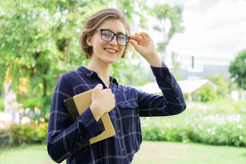 A woman wearing glasses and a plaid shirt is holding a book