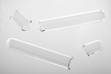 Two broken glass test tubes on a white surface