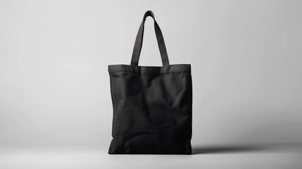 A black tote bag mockup with long handles on a plain grey background, ideal for showcasing branding or design artwork in a professional presentation.
