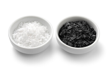 Pair of bowls with black and white sea salt flakes close up isolated on white background