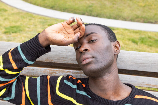 Young man showing signs of hypoglycemia on a park bench