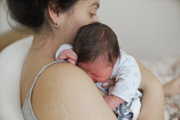 Mother cradling her newborn baby close, enjoying the early moments of bonding and tenderness in...