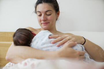 Mother cradling her newborn baby close, enjoying the early moments of bonding and tenderness in...