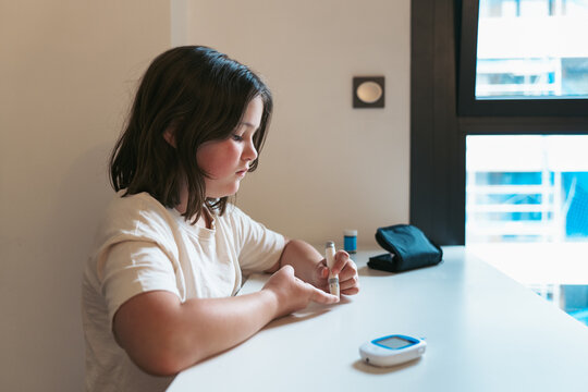 Young girl checking blood sugar level at home