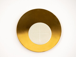 Gilded paten with white altar bread - holy bread, white background
