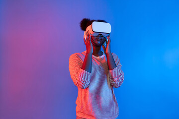 Young African woman with VR in presentation through metaverse study online neon studio lighting...