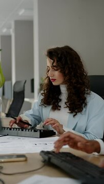 Business woman examining paperwork in an office setting with her computer own. Professional shuman reviewing documents at dsc.