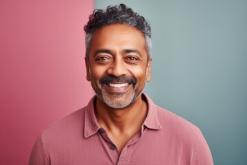 Obraz premium Portrait of a satisfied indian man in his 40s smiling at the camera in pastel or soft colors background