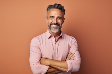 Obraz premium Portrait of a happy man in his 40s with arms crossed in front of pastel or soft colors background