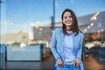 Portrait of happy businesswoman looking at camera. Successful proud woman in city street at sunset....