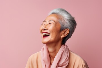 Fototapeta premium Portrait of a tender asian woman in her 70s laughing isolated in pastel or soft colors background