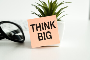 Think big text on adhesive note stick on a flower pot on white background.