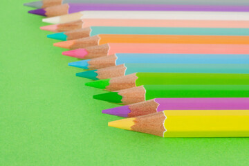 Colored pencils in row on a green background