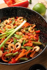 Shrimp stir fry with vegetables in wok on table, closeup