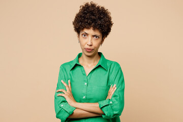Young frowning mad sad woman of African American ethnicity wears green shirt casual clothes hold...