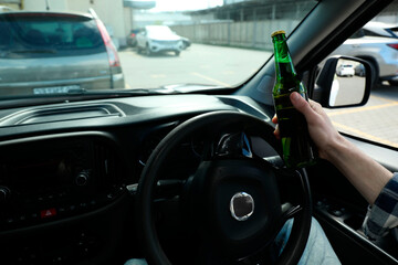 Fototapeta premium Man with bottle of beer driving car, closeup. Don't drink and drive concept