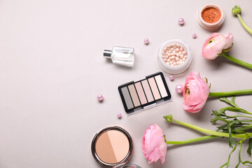 Flat lay composition with different makeup products and beautiful spring flowers on gray background, space for text