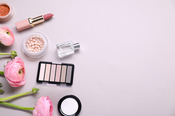 Obraz na płótnie Canvas Flat lay composition with different makeup products and beautiful spring flowers on gray background, space for text