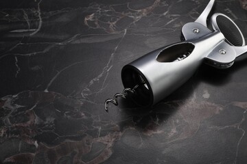One wing corkscrew on black marble table. Space for text