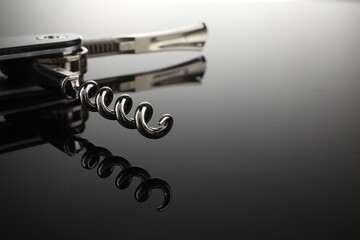 One corkscrew (sommelier knife) on mirror surface, closeup. Space for text