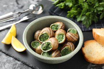 Delicious cooked snails served on grey table, closeup